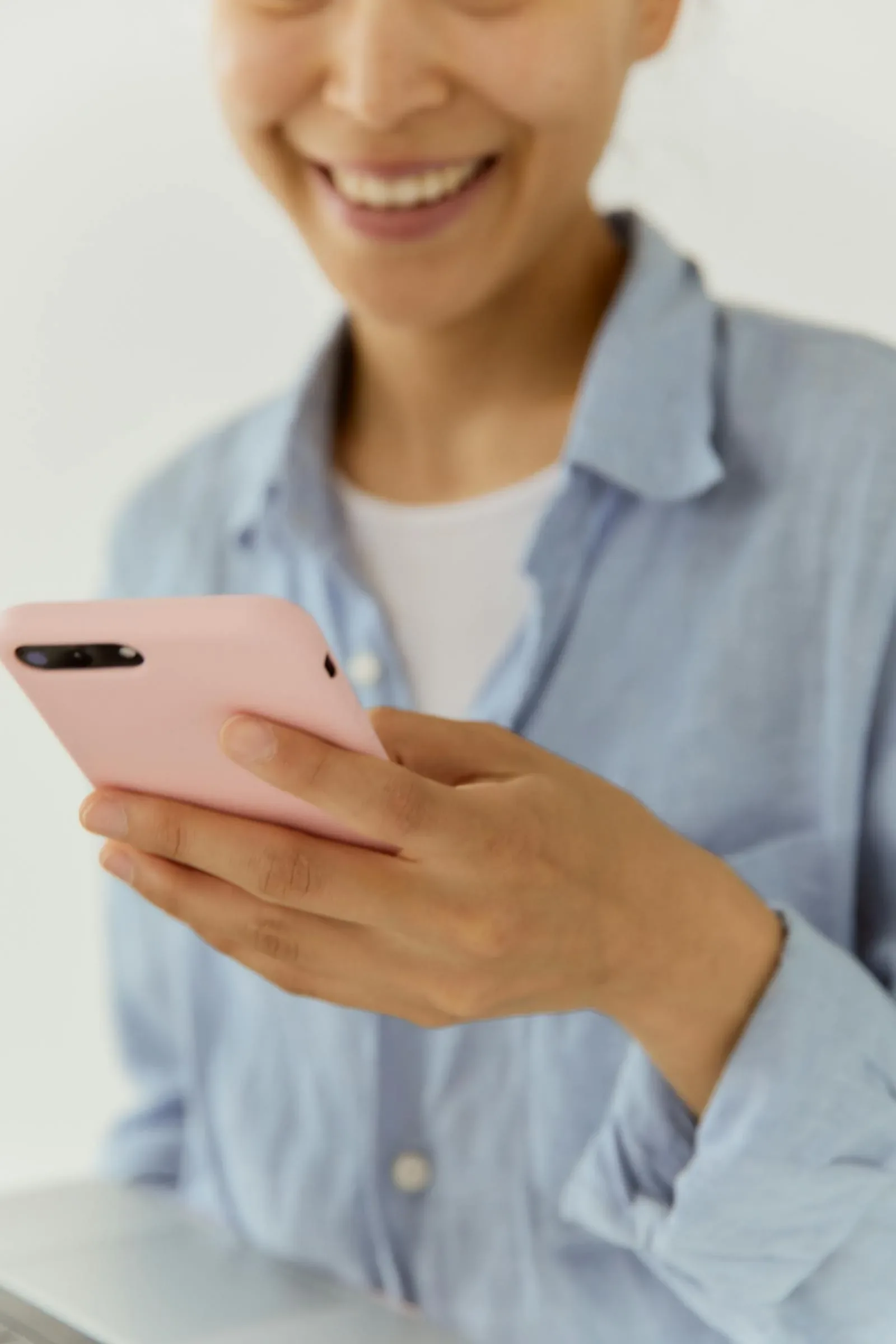 A person smiling while looking at a phone, using a healthcare service