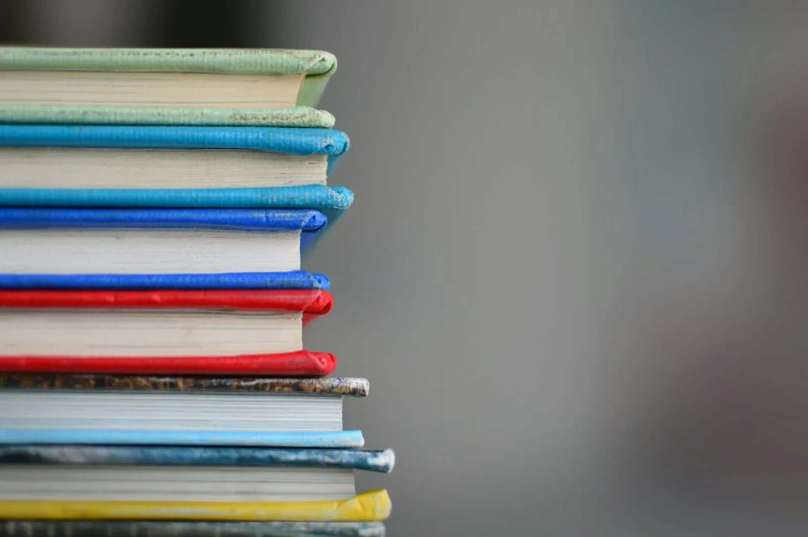 Stack of textbooks and paperwork on a school office desk